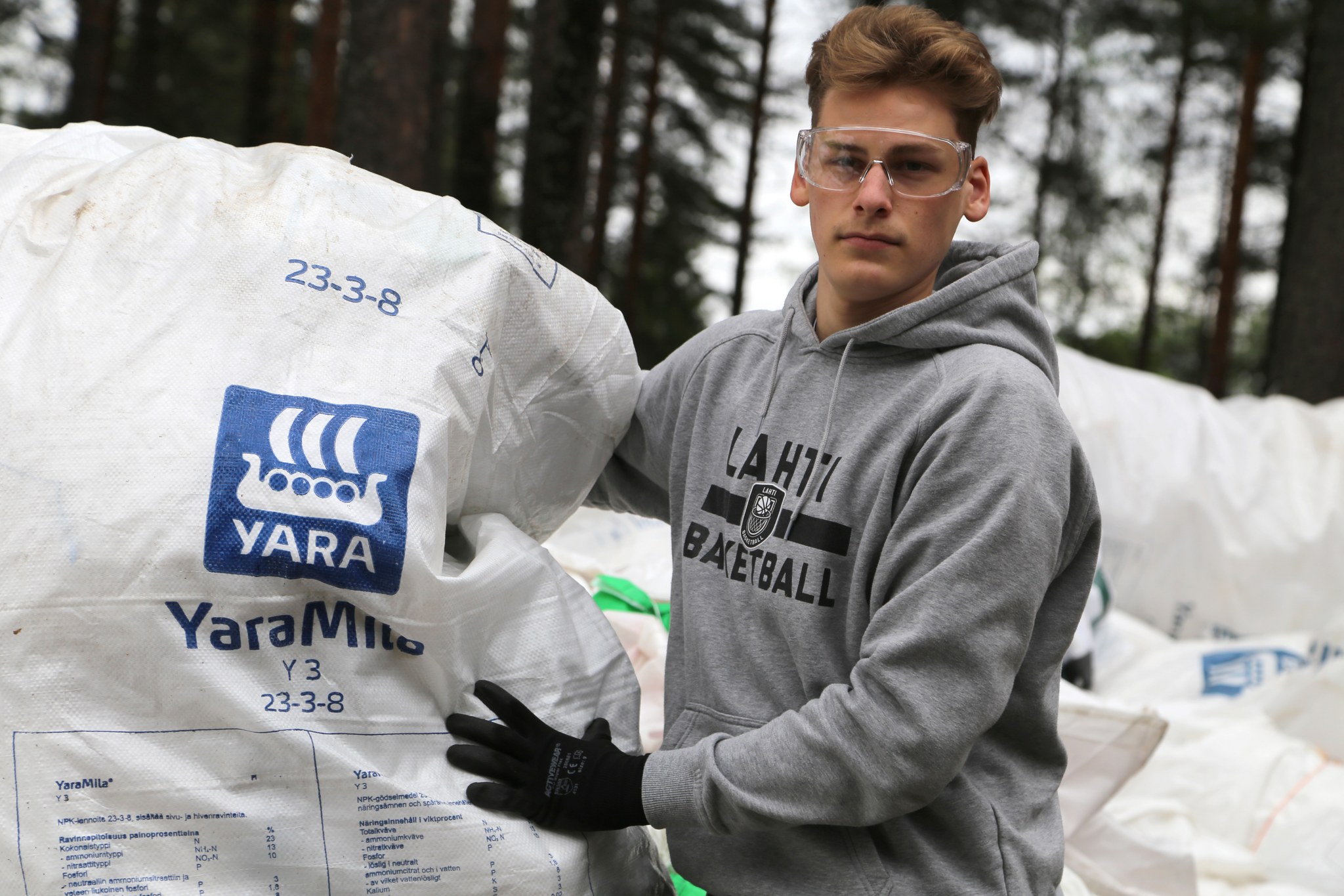 Nuori mies pitelemässä kädessään lannoitesäkkiä Reilu teko -lannoitesäkkikeräykseen.