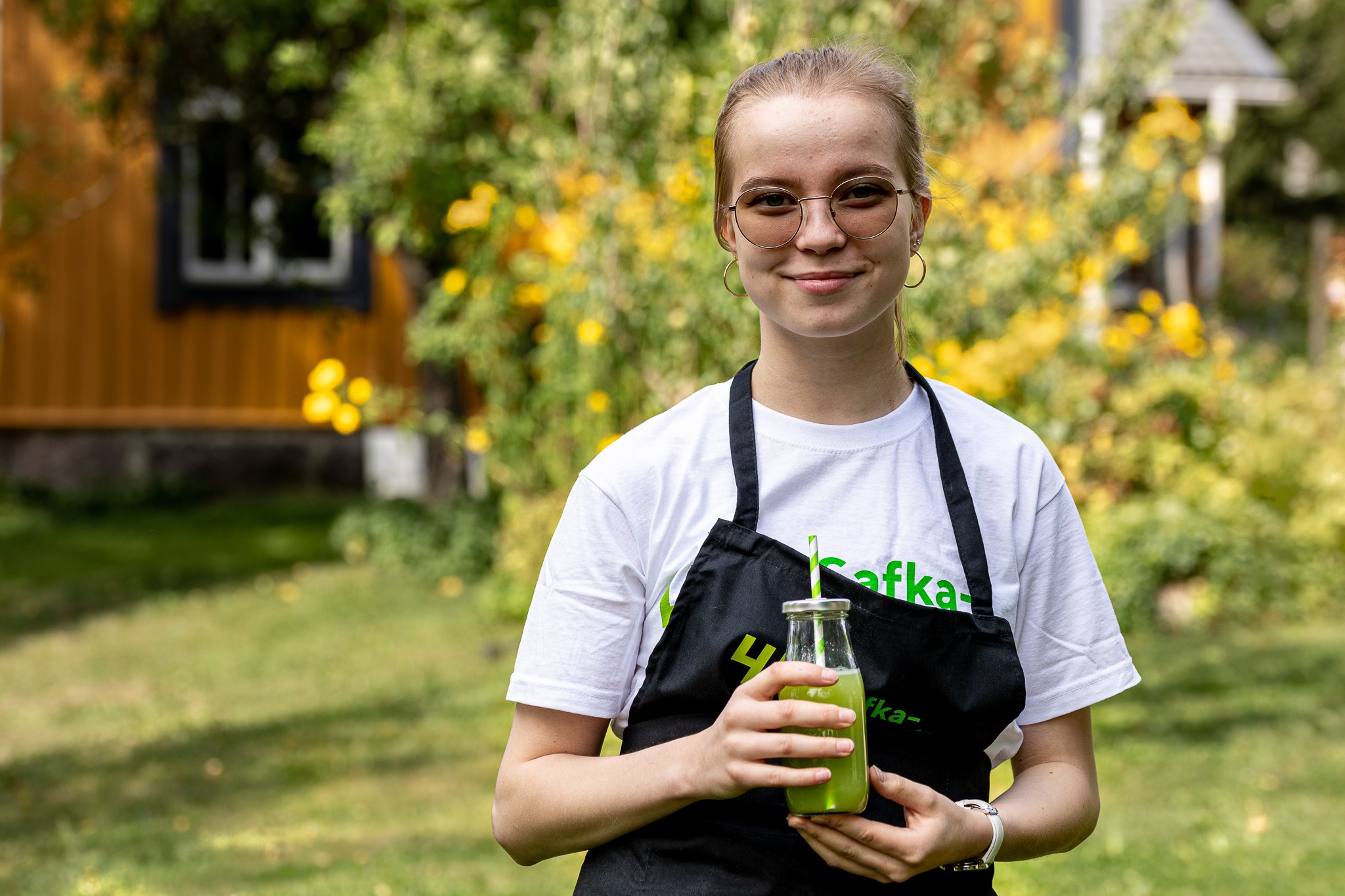 Nuori nainen seisomassa ulkona käsissään vihreä smoothie.
