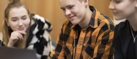 Kolme henkilöä katsoo läppäriä