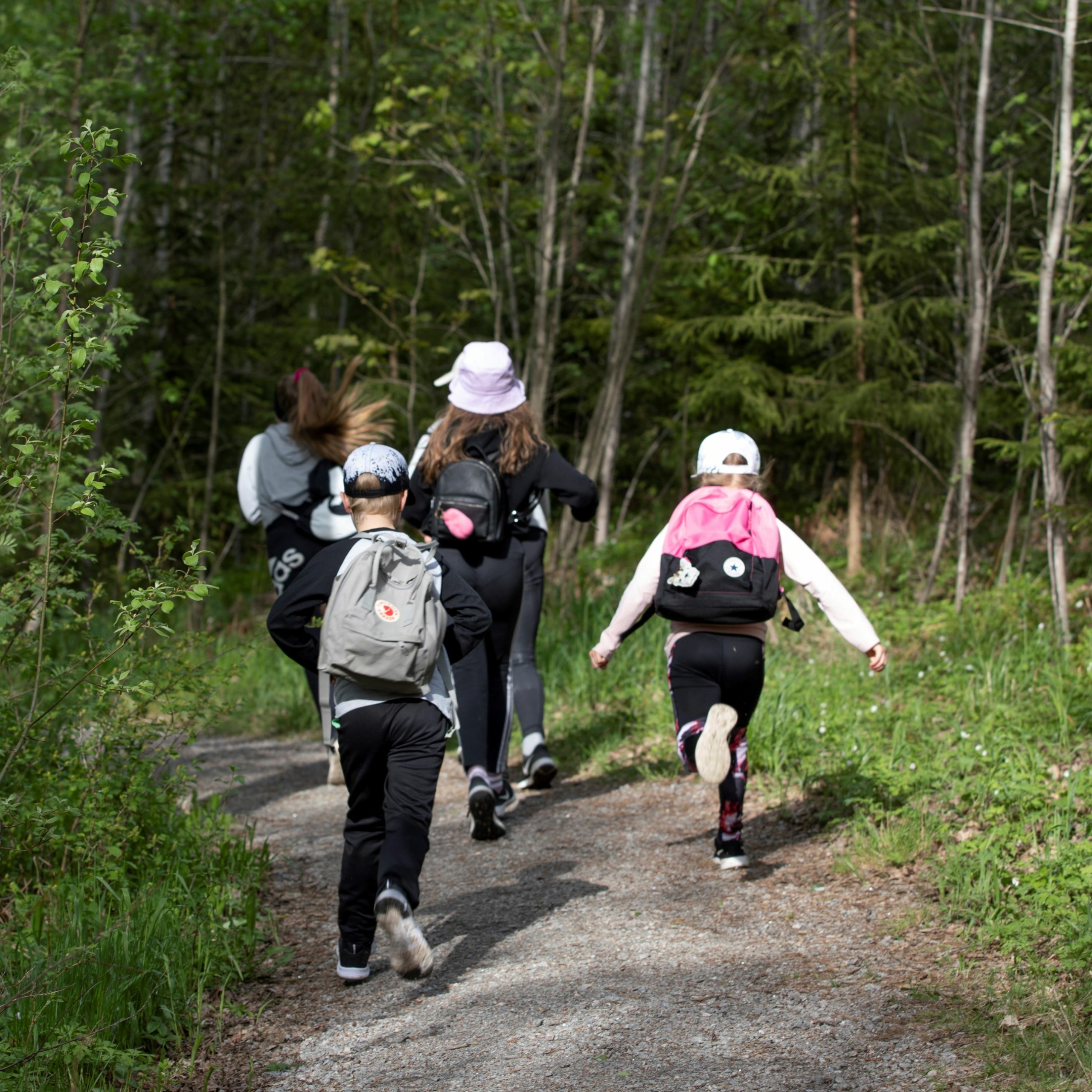 Lapset juoksevat metsäpolulla.