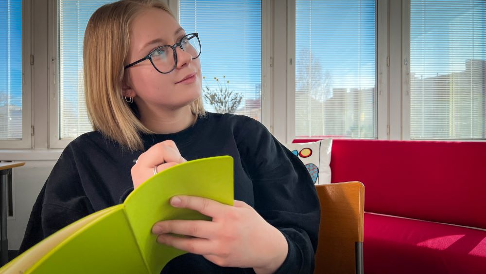 Tyttö kirjoittaa vihkoon muistiinpanoja.