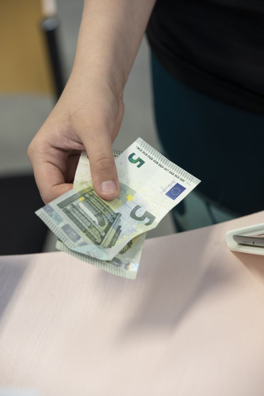 Yrittäjä ojentaa kaksi viiden euron seteliä.