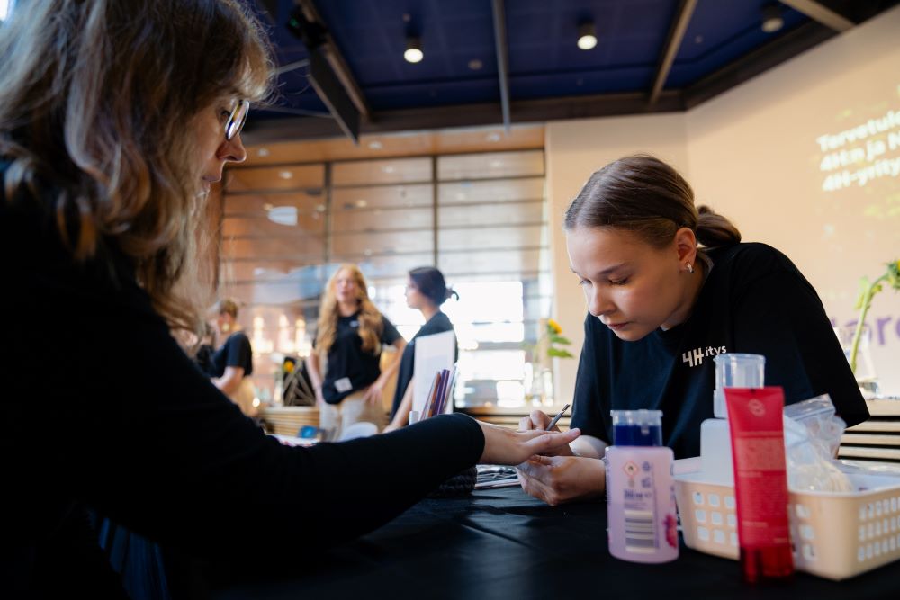 4H-yrittäjä lakkaa asiakkaan kynsiä myyntitapahtumassa.