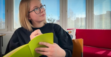 Nuori nainen kirjoittaa vihreään vihkoon.